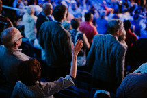 people with hands raised at a worship service 