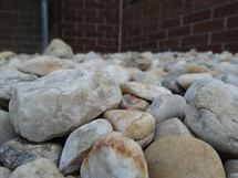 White and beige rocks in rock bed beside house in lawn