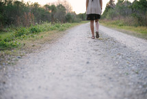 woman walking on a gravel road 