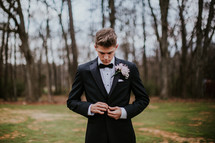 teen boy buttoning a tuxedo 