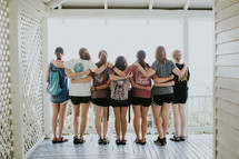 teen girls standing together with arms around each other on a porch 