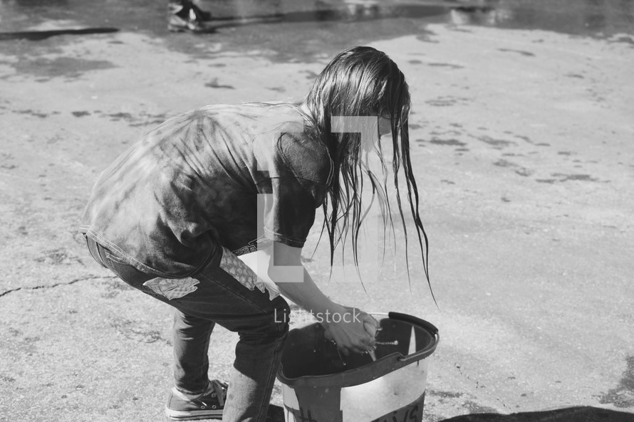 girl wetting a sponge in a bucket for a car wash 
