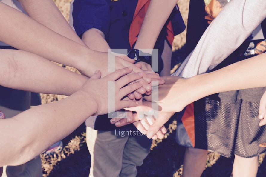 a group of children with hands stacked on top of each other 