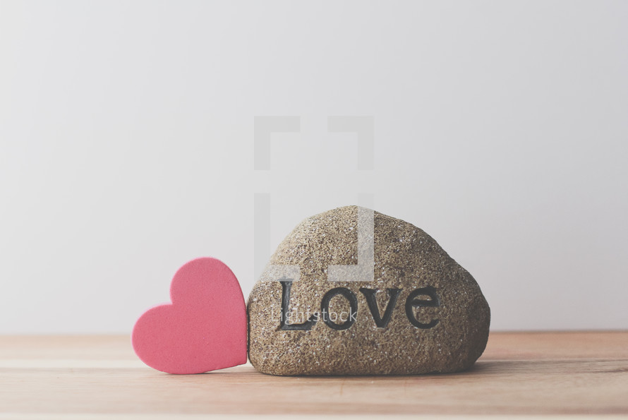 a rock with the word with the word love and a red heart 
