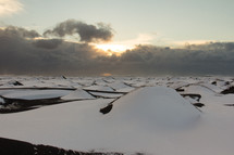 Snow covered sand dunes on an Icelandic black beach on the south coast near Vik. A storm is coming in during sunset.