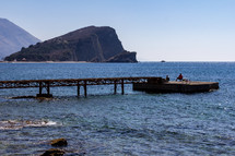 Two fisherman attempt to catch fish at the end of a pier on Olt Town Beach in Budva, Montenegro