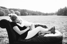Mother and child on a couch in a field of grass.