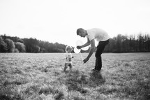 Father and son with balloons in a field of grass.
