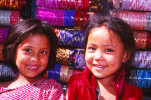 smiling young girls in front of spools of yarn 