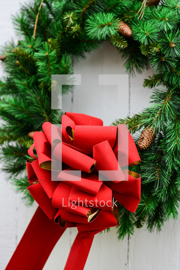 An evergreen Christmas wreath with a big red bow.
