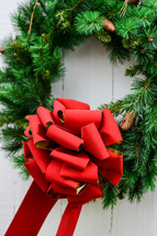 An evergreen Christmas wreath with a big red bow.