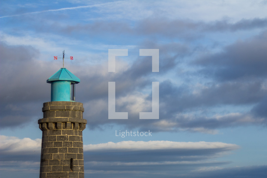 weather vane on a tower - top of Teignmouth lighthouse against a cloudy sky