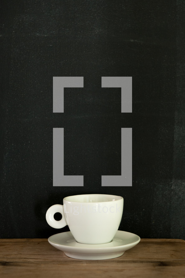 Espresso cup on a saucer against a chalk wall.