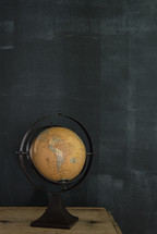 A globe with the continent of South America showing against a chalk wall.