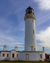 Mull of Galloway lighthouse and surrounding buildings in Dumfries and Galloway, Scotland, United Kingdom under a blue sky with white clouds