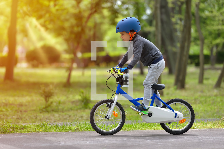 Active child wearing bike helmet riding a bike at a park 