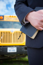 man holding a Bible and school bus 