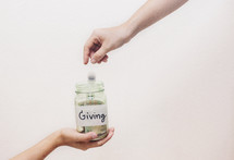 putting money in a giving jar 