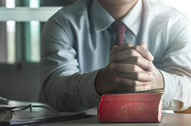 businessman with praying hands on a Bible 