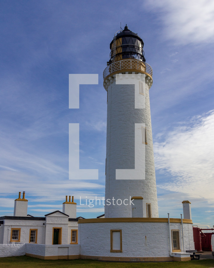 Mull of Galloway lighthouse and surrounding buildings in Dumfries and Galloway, Scotland, United Kingdom under a blue sky with white clouds