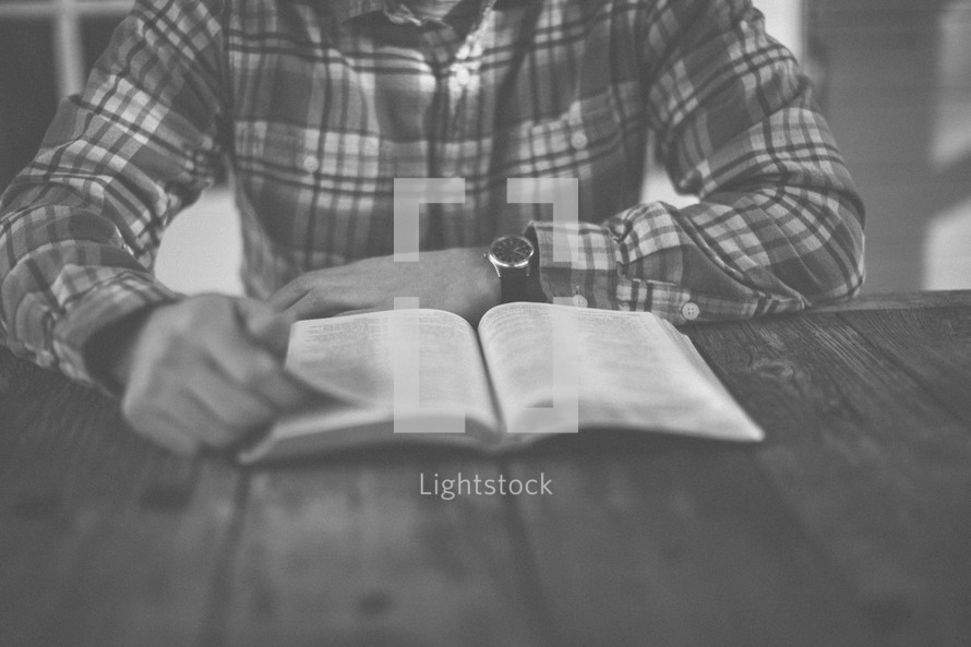 A man sitting at a table reading the Bible