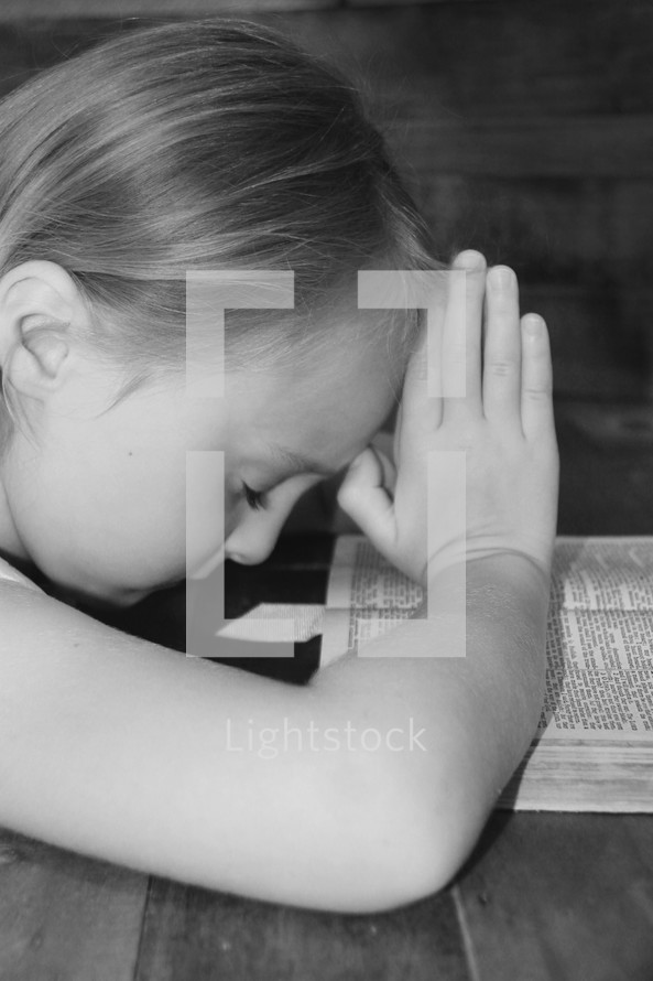 girl child praying over a Bible 