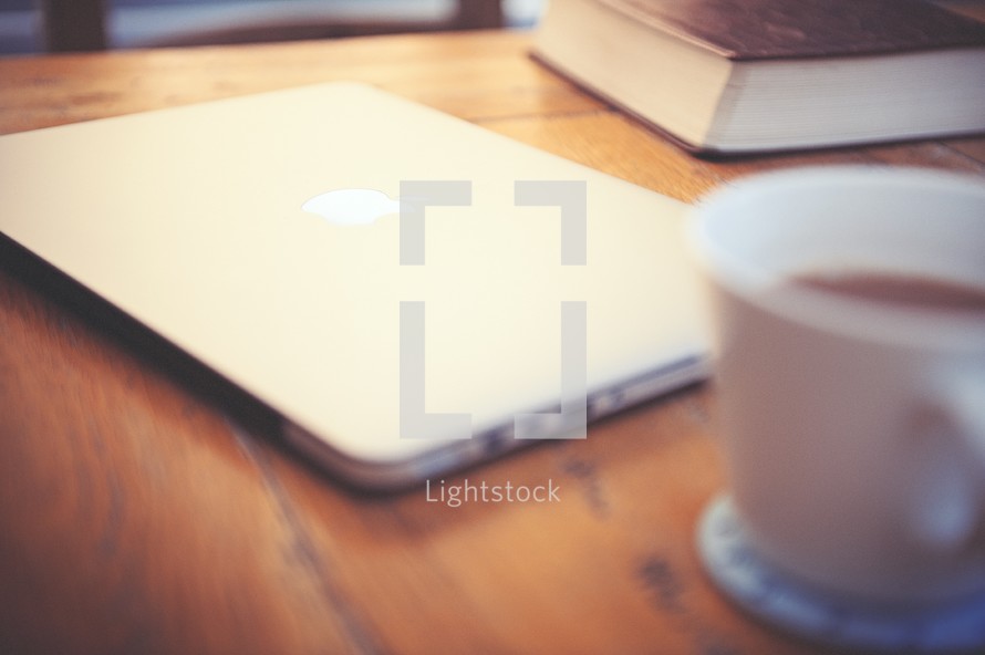 laptop, Bible, and coffee cup on a table 
