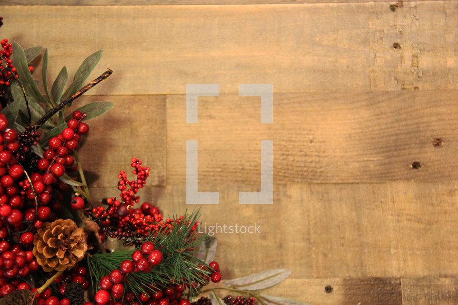 Red berries and greenery on a Christmas wreath over a wooden background 