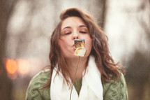 Woman blowing on a toasted marshmallow.