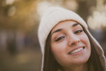 A young smiling girl wearing a white beanie