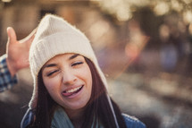 A young woman sticking her tongue out and wearing a white beanie