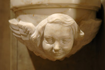 Marble face and wings of an gothic angel on a column