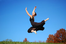 dance leaping in the air, tree with red leaves in the background