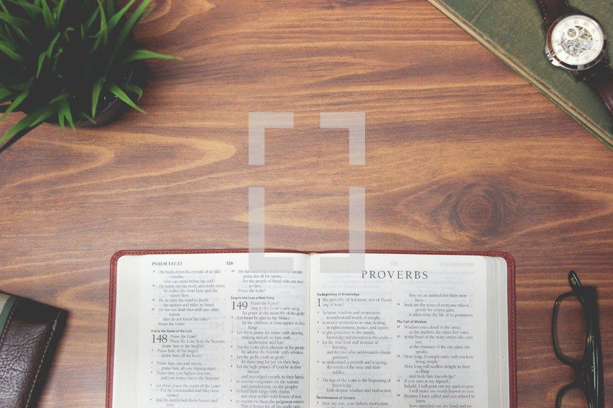 open Bible and reading glasses on a wood table - Proverbs 