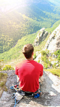 man siting on a rock on a mountain under sunlight 