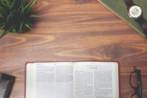 open Bible and reading glasses on a wood table - Luke 