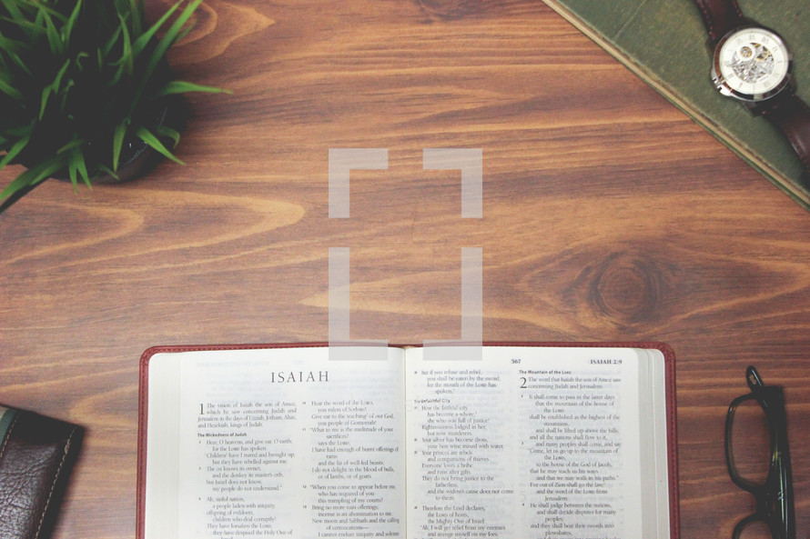 open Bible and reading glasses on a wood table - Isaiah