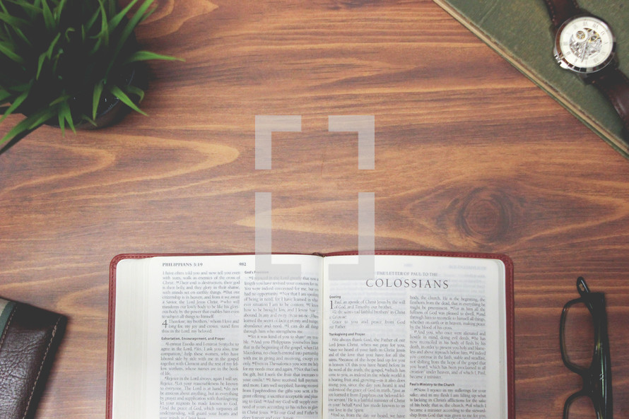 open Bible and reading glasses on a wood table - Colossians 