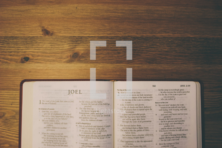Bible on a wooden table open to the book of Joel.