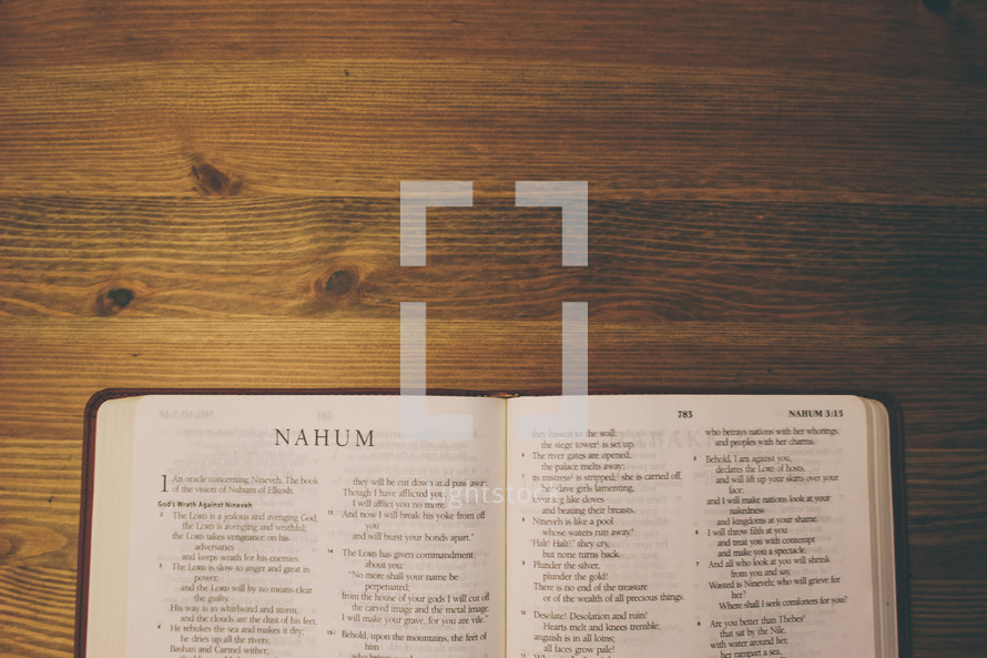 Bible on a wooden table open to the book of Nahum.