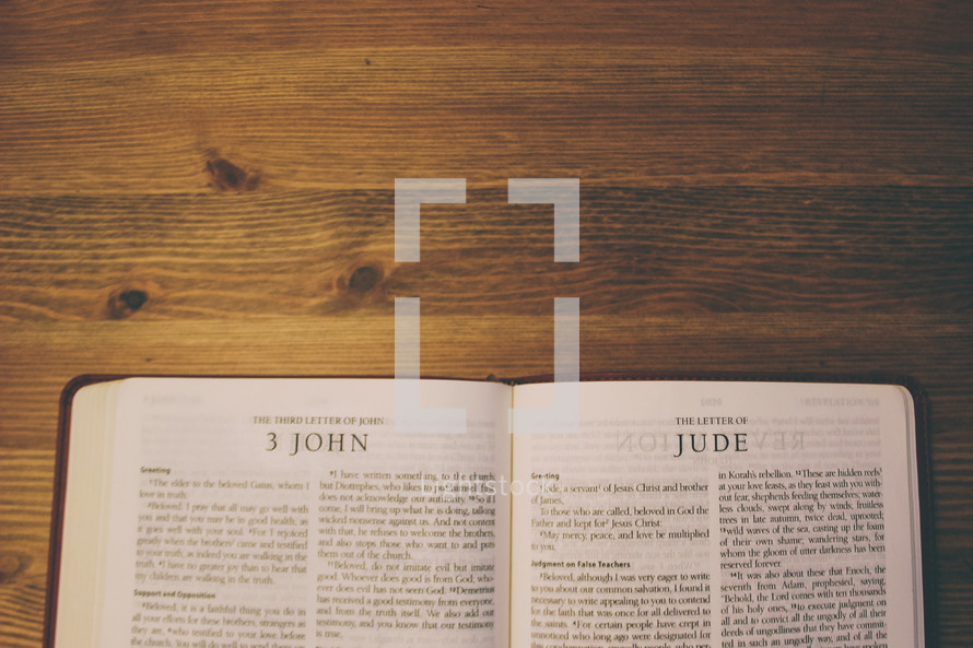 Bible on a wooden table open to the book of 3 John and the Letter of Jude.