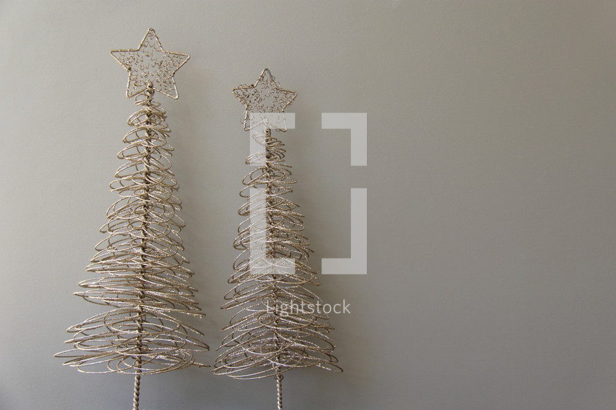 Gold wire Christmas trees against a grey background