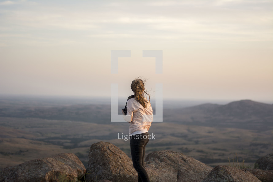 woman with a camera standing on a mountain top 