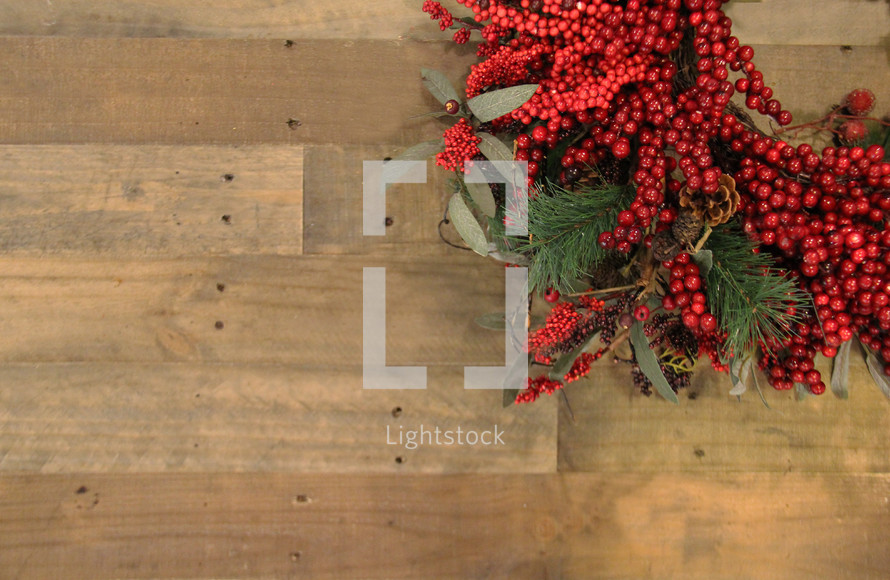 Red berries on a Christmas wreath against a wooden background 