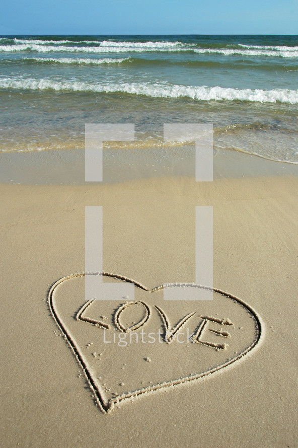 love and heart drawn in the sand on a beach 