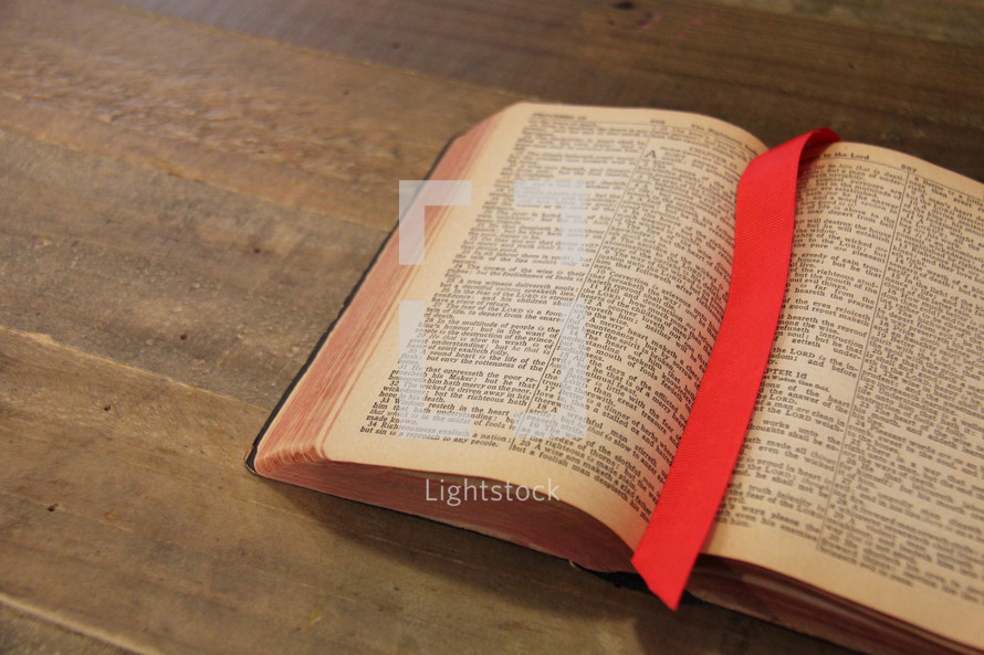 Bookmark between the open pages of a Bible on a wooden desk