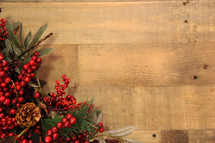 Red berries and greenery on a Christmas wreath over a wooden background 