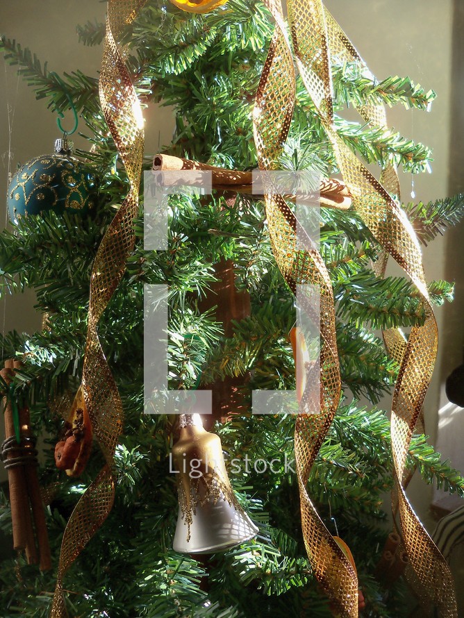 A traditional Christmas tree with silver bells, brown cascading ribbons glowing and bathed in sunlight.