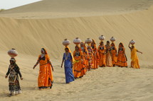 female Hindu women walking with water jugs on their heads 