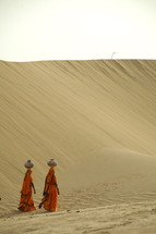 Hindu women walking through sand with water jugs on their heads